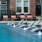a pool in front of a brick building with a fountain in the front